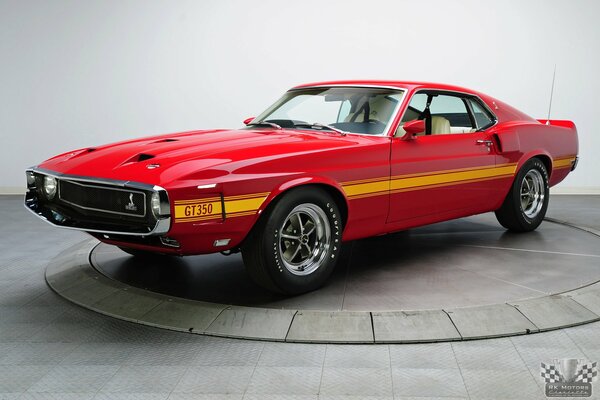 A classic red car stands on a pedestal