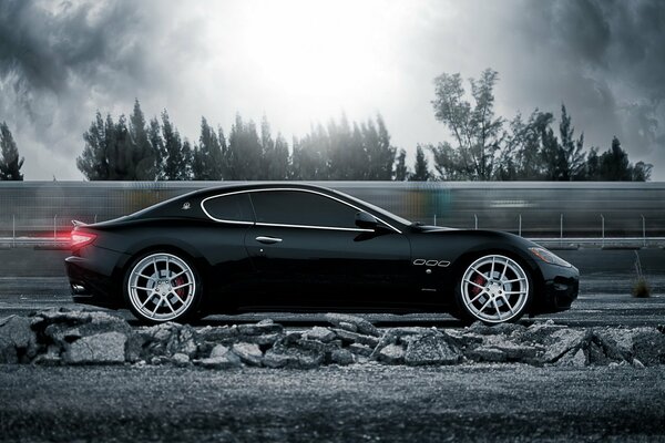 Noir maserati chevauche sous les rayons du soleil