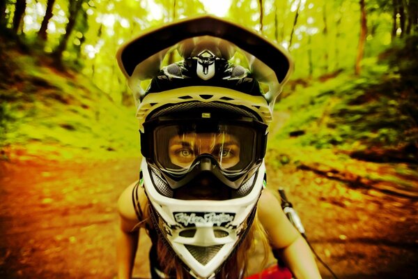 Chica en un casco en una bicicleta en el bosque