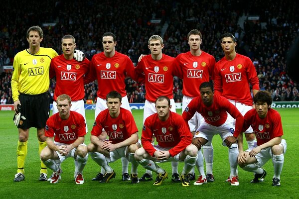 Auf dem Fußballplatz posieren Fußballer in roten Trikots für ein Foto