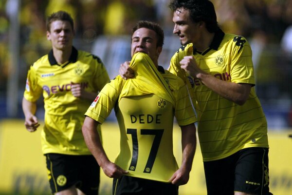 Football players in yellow uniforms are happy to win