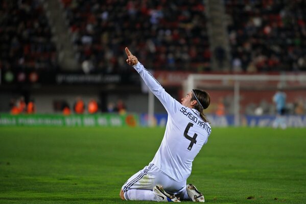 Sergio Ramos si siede sul campo di calcio e mostra la mano in su