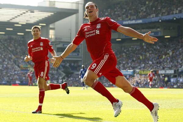 Dwóch piłkarzy klubu Liverpool radośnie biegnie po boisku