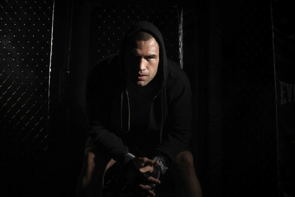 A man in a black hoodie on a black background