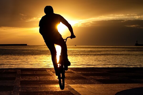 Un gars au coucher du soleil Monte un vélo