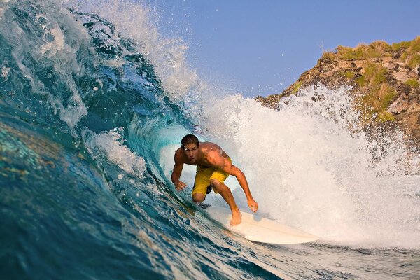 Schöner Surfer unter einer riesigen Welle