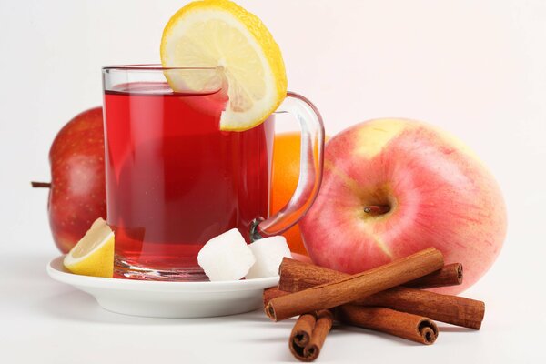 A mug of compote with apples, a couple of pieces of sugar, cinnamon and lemon