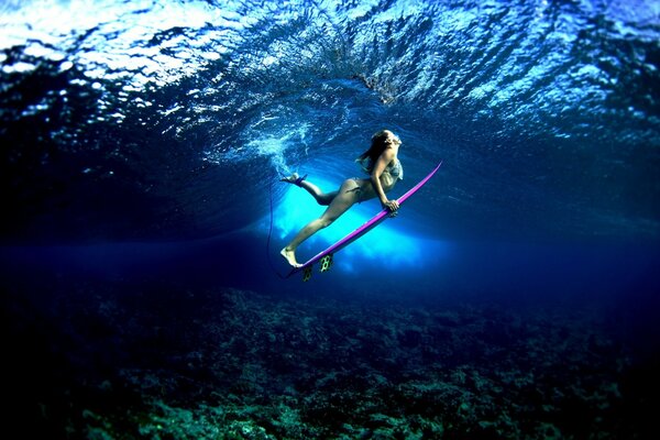 Chica surfista en las profundidades del mar azul