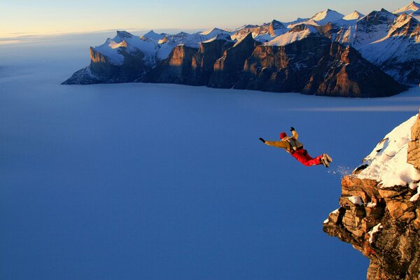 A parachutist jumps from a high mountain at dawn