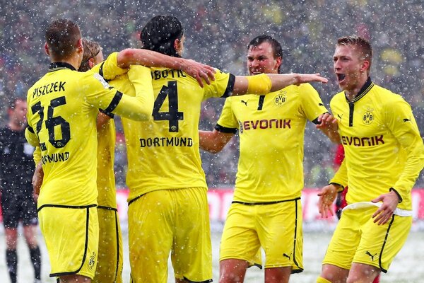 Les hommes en uniforme de sport jaune jouent au football