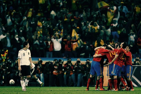 A football match with a stadium full of fans. Football players are standing on the field, hugging