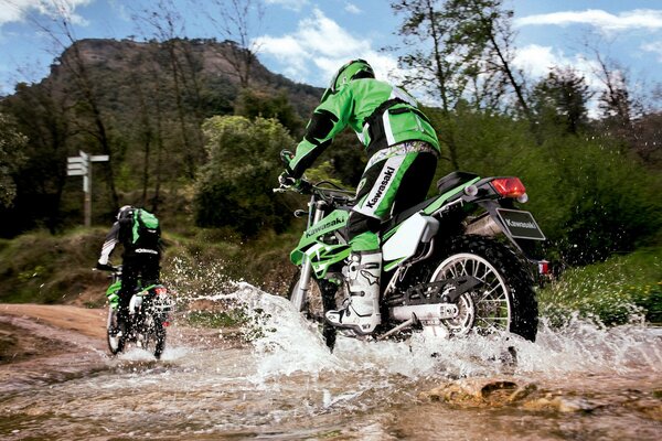 Zwei Motorradfahrer in Schwarz-Grün überfahren einen Bergbach