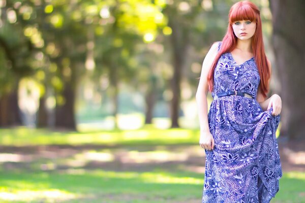 Red-haired girl in a purple dress in the park