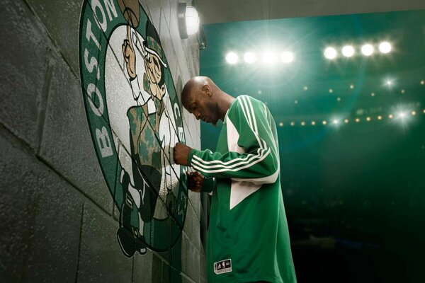 Le basket-ball en uniforme vert prie devant l emblème du Club