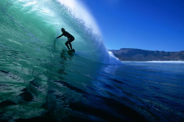 Surfer under the wave of the blue ocean