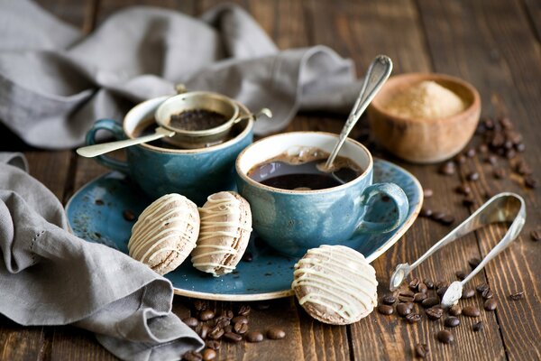A couple of mugs of coffee with macaroons and coffee beans