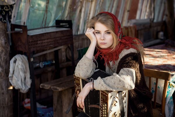 Sad girl in a scarf with an accordion