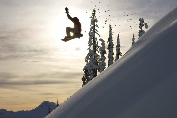 Salto extremo del snowboarder en medio del sol de invierno