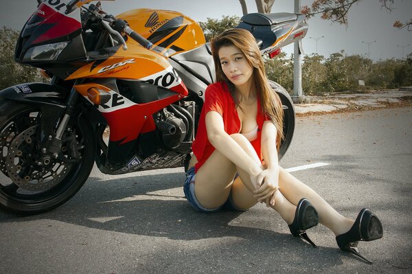 Femme asiatique posant sur fond de moto