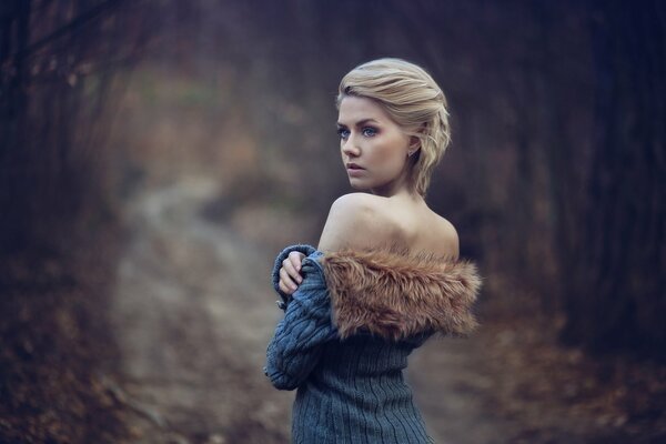 Blonde en veste avec de la fourrure sur les épaules nues