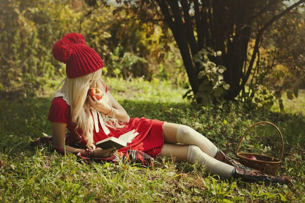 Ragazza con cappuccio rosso che mangia mela nella foresta