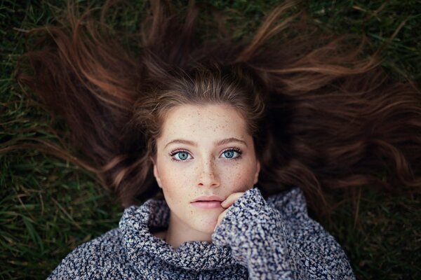 The thoughtful look of a girl in a large knitted sweater