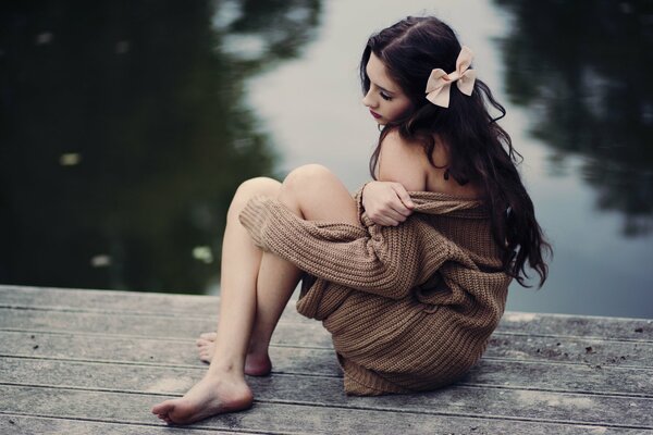 Girl with a bow on the bridge by the lake