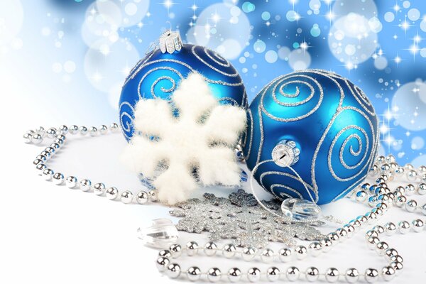 Декор для Нового года. Красивые синие шары с белыми узорами. Белые и серебристые снежинки с серебристой гирляндой