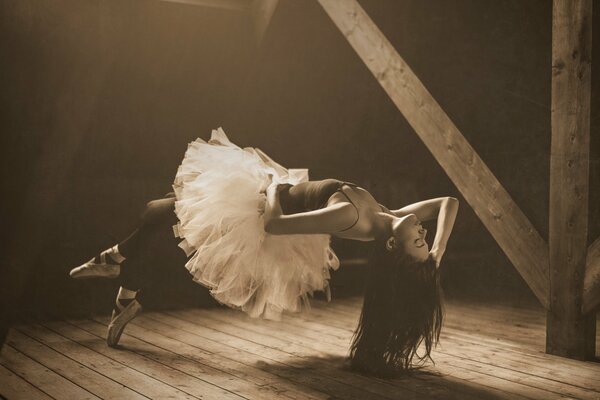 Bailarina en tutú blanco y medias negras levitando en el ático