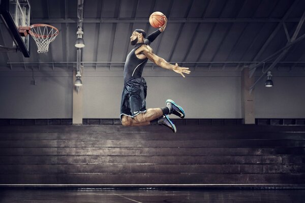 Basketballspieler mit Ball im Sprung vor dem Ring