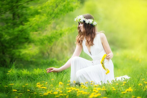 The girl collects dandelions in a wreath