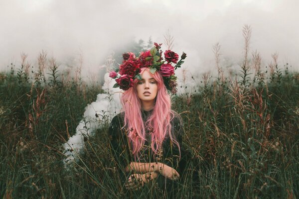 A girl with pink hair and a wreath of bright flowers in a field