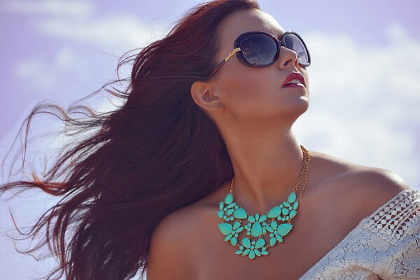 A girl in sunglasses and with an ornament on her neck