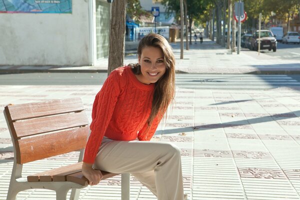 Chica radosnaya en el banco suéter rojo