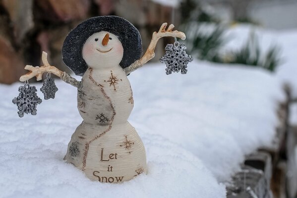 Piccolo pupazzo di neve sorridente in un cappello che tiene i giocattoli del fiocco di neve