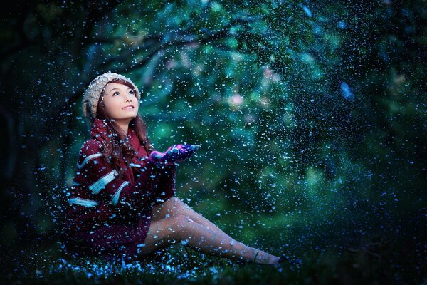 Fille avec des regards asiatiques attrape des flocons de neige avec ses paumes