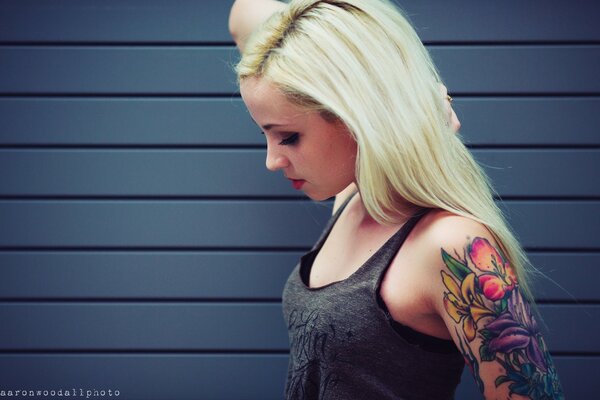 A girl with blonde hair and a tattoo of flowers