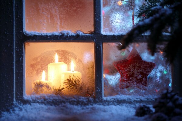 Kerzen am Weihnachtsbaum vor dem Fenster