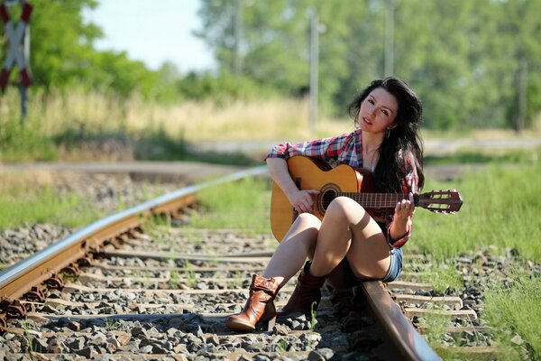 Cute girl with guitar on rails