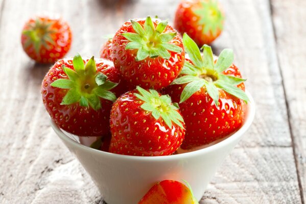 Las fresas rojas yacen en un cuenco sobre una mesa