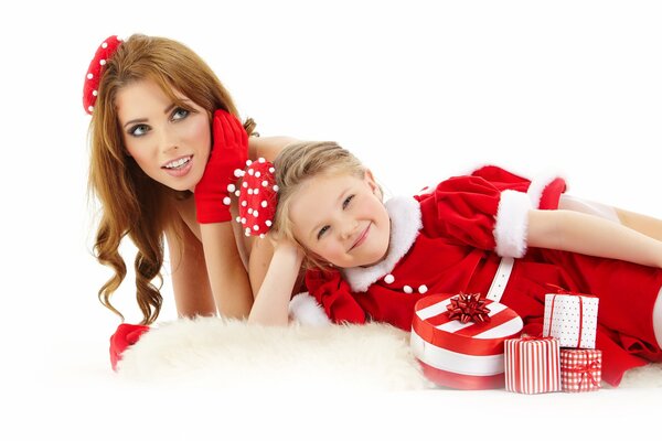 A girl and a girl in Christmas costumes pose with holiday boxes