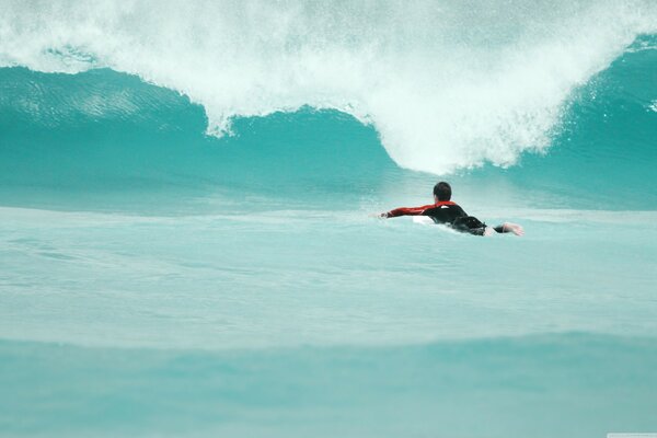 Surfista che nuota su un onda di colore azzurro