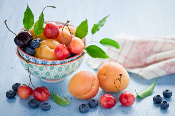 Stillleben aus Beeren und Früchten mit Schalen und Servietten