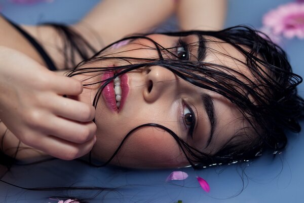 The face of a beautiful girl lying in the water with petals