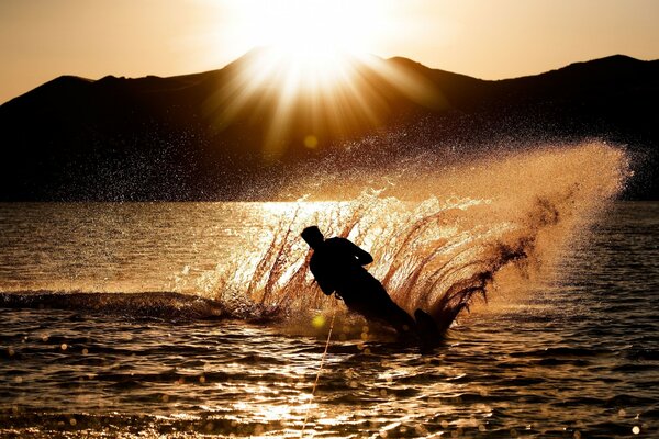 Homme sur le ski nautique au coucher du soleil