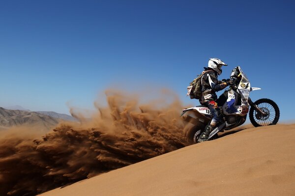 Moto da corsa con pilota nel deserto di Dakar