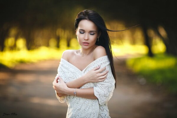 Foto de una morena frágil en un suéter blanco