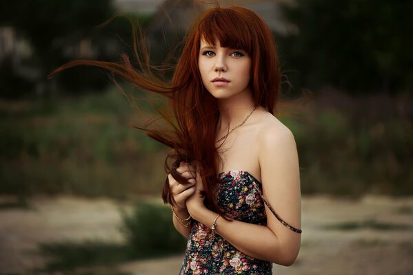 Rousse jolie fille avec des cheveux en développement et une robe de fleur