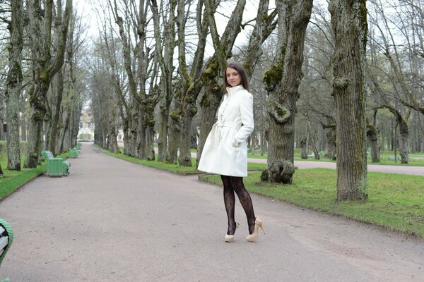 Fille en manteau blanc dans le jardin de la ville