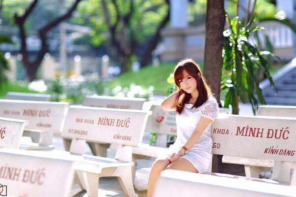 In summer, an Asian girl is sitting on the street